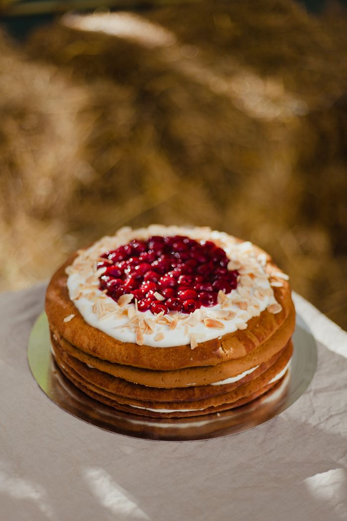 A close view of a rustic layer cake topped with cream and jam.