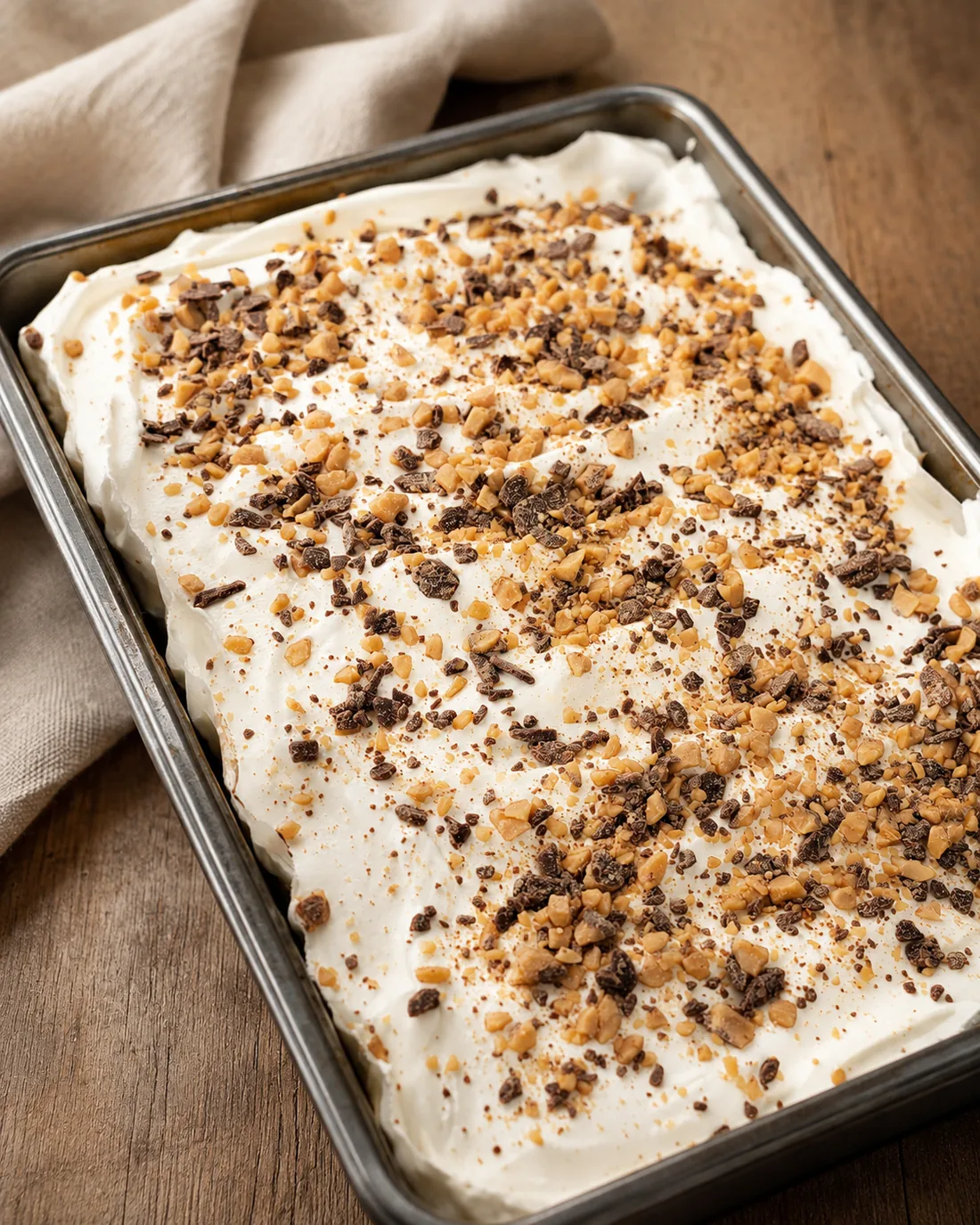 A homemade sheet cake topped with whipped cream and crushed toffee.